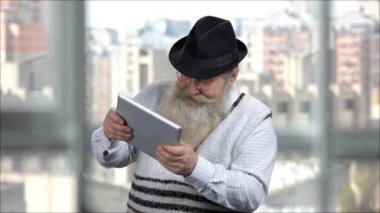Yaşlı sakallı adam çocukken tablette video oyunu oynuyor..