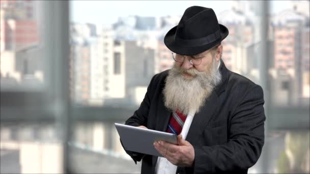 Hosszú szakállú férfi sötét öltönyben tabletta segítségével. — Stock videók