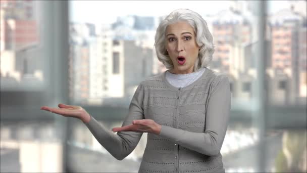 Överraskad äldre dam visar kopieringsutrymme. — Stockvideo