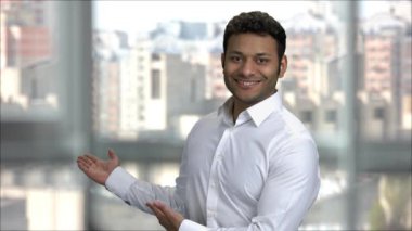 Gülümseyen genç Hintli adam iki koluyla işaret ediyor..