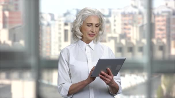 在办公室使用数码平板电脑的灰发女商人. — 图库视频影像