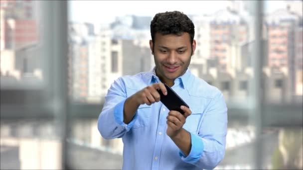 Fiatal indiai irodai dolgozó élvezi videojátékok a telefonján. — Stock videók