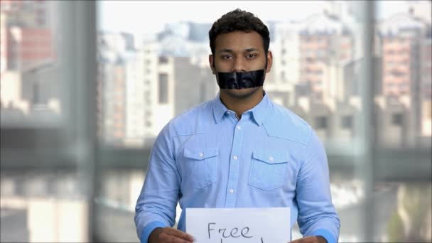 Arabic man with taped mouth showing free speech banner. — Stock Video