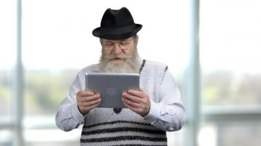 Yaşlı emekli adam tableti sağa sola hareket ettiriyor, yarış oyunları oynuyor..