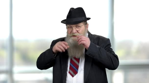 Alter Senior glättet seinen langen Bart und Schnurrbart. Reicher greiser Opa mit schwarzem Hut und Anzug. — Stockvideo