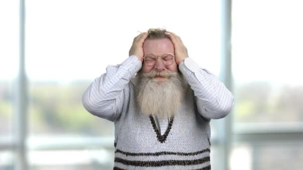 Portret van een oude man met een baard met een sterke hoofdpijn. — Stockvideo