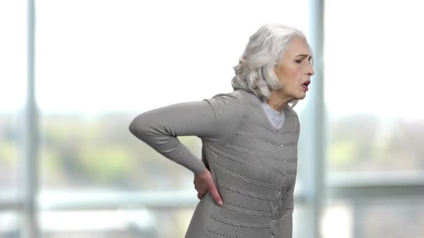 Stara, szczupła kobieta cierpiąca na ból pleców. — Wideo stockowe