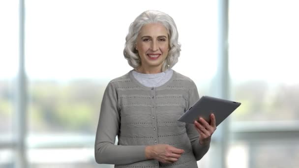 Portrait of and old slim lady holding tablet pc and talking. — Stock Video
