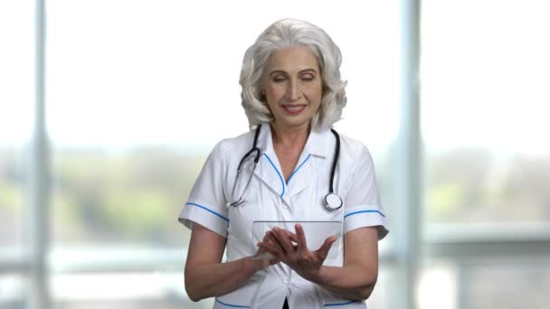 Retrato de una vieja doctora feliz usando tableta transparente pc . — Vídeo de stock