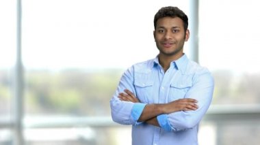 Kollarını kavuşturmuş genç Hintli adam baş parmağıyla geriye bakıyor..