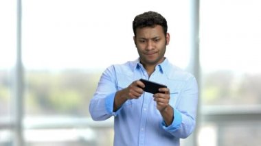 Genç hevesli Hintli adam akıllı telefonuyla video oyunları oynuyor..