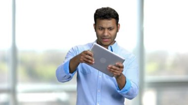 Hindu adam yüz ifadeleriyle tablet bilgisayarında oyun oynuyor.