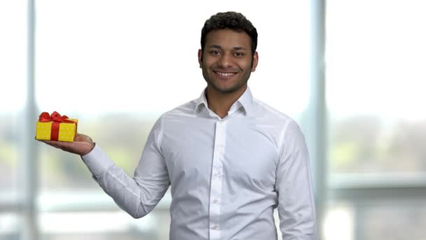 Portrait of an young hadnsome indian man holding yellow gift box. — Stock Video