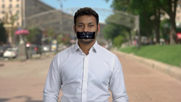 Portrait of a young indian man with taped mouth in the city. — Stock Video