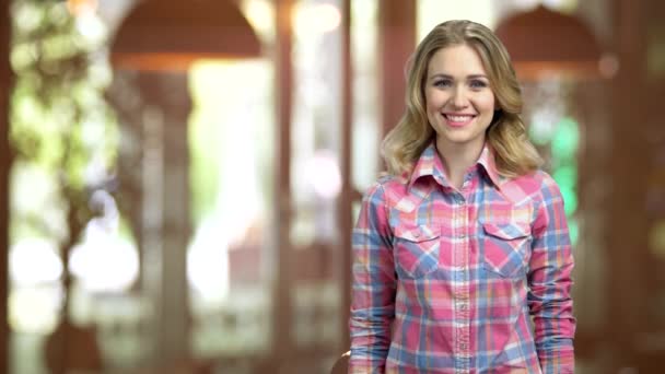 Jovem sorridente menina em uma camisa casual apontando para trás com o polegar . — Vídeo de Stock