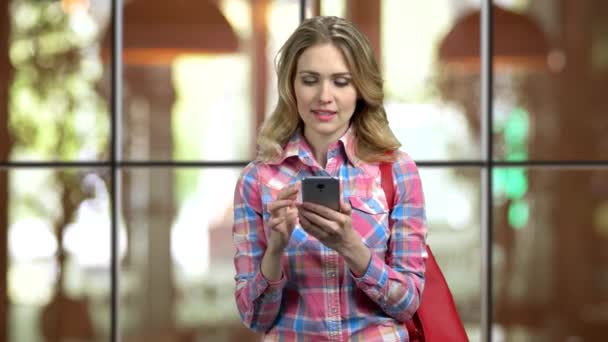 Young girl in casual cloth and purse entartaining with social media on phone. — Stock Video