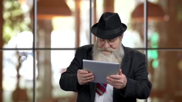 Старий бородатий чоловік з планшетним ПК надзвичайно збуджений . — стокове відео