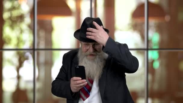 Extrem aufgeregter alter Mann im Anzug hat Spaß mit Smartphone. — Stockvideo