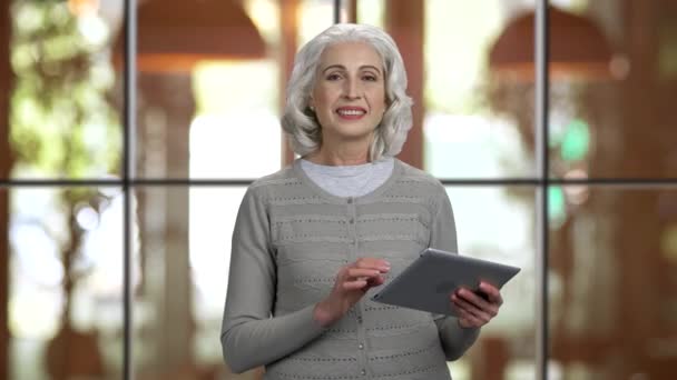 Pozitív vonzó idős hölgy gazdaság tabletta pc és beszél. — Stock videók