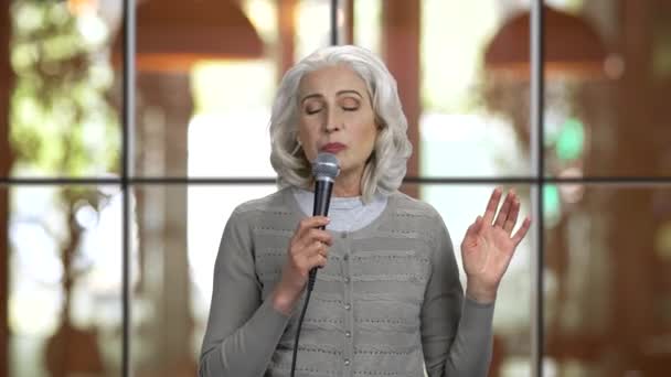 Porträt einer alten Dame, die ein Lied mit Mikrofon vorträgt. — Stockvideo