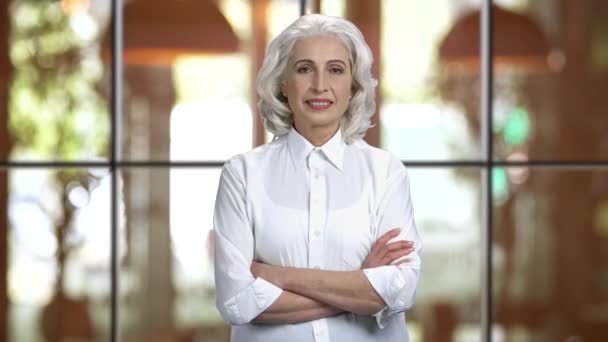 Old grey-haired lady wearing white shirt folding her arms. — Stock Video
