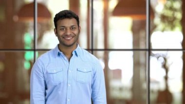 Genç gülümseyen kahverengi tenli adam avuç içlerini kaldırıyor, kopyalanmış uzayı gösteriyor.