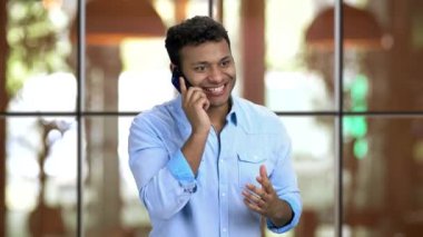 Lokantada telefonla konuşan mutlu kahverengi tenli adam..