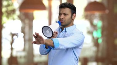 Genç kahverengi tenli ustabaşı megafonla konuşuyor..