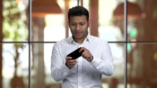 Emocionado chico de piel oscura jugando juegos en su teléfono inteligente . — Vídeos de Stock