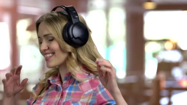 Ung flicka lyssnar på musik i stora hörlurar. — Stockvideo