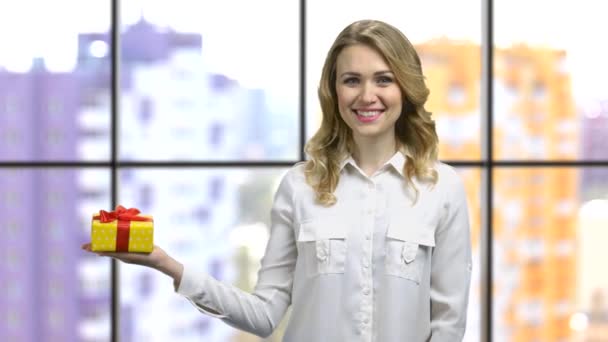 Chica joven con una camisa blanca apuntando a la caja de regalo . — Vídeos de Stock