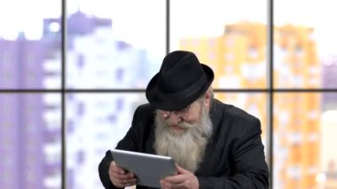 Yaşlı zengin işadamı tablet bilgisayarda olumlu duygularla oyunlar oynuyor..