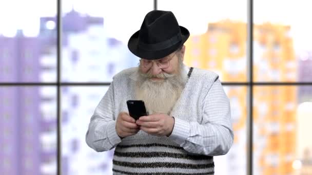 Oud gepensioneerd opa sms 'en op smartphone. — Stockvideo