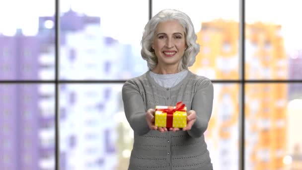 Oude vrouw geven geschenk doos met beide handen. — Stockvideo