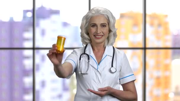 Senior vrouwelijke arts toont blik pillen en duim omhoog. — Stockvideo