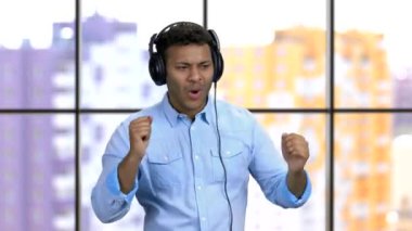 Koyu tenli, kulaklıklı genç bir adam rock müzik dinliyor..