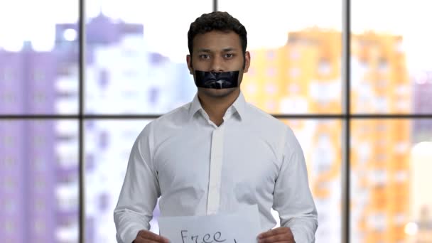 Νεαρός σκουρόχρωμος ακτιβιστής με το στόμα του κολλημένο δείχνει πανό. — Αρχείο Βίντεο
