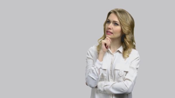 Young businesslady looking up and thinking holding her chin. — Stock Video