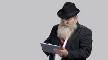 Eski işadamı tablet bilgisayar ekranına dokunuyor.