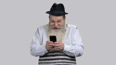 Yaşlı adam akıllı telefonuyla internette eğleniyor..