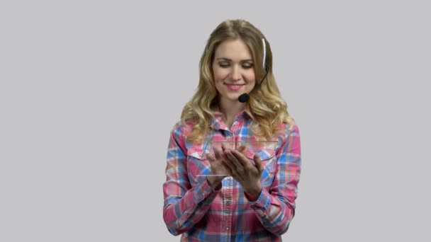 Helpdesk worker, young girl with headset and blank glass tablet. — Stock Video