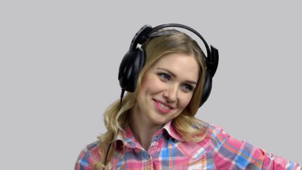 Młoda pozytywna kobieta nosi słuchawki i rozmawia. — Wideo stockowe