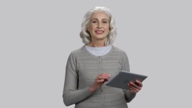 Tablet bilgisayarlı yaşlı bayan konuşma yapıyor..