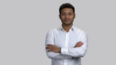 Kollarını kavuşturup sol eliyle işaret eden mutlu Hintli adam..