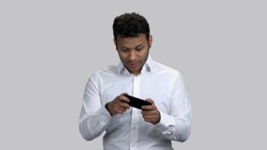 Koyu tenli çocuk akıllı telefonuyla video oyunu oynuyor..