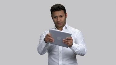 Tabletinde video oyunu oynayan çok heyecanlı koyu tenli bir adam..