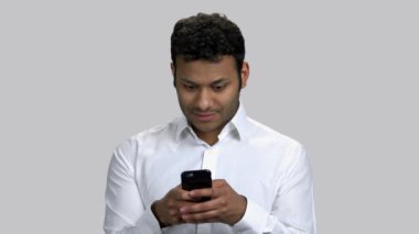 Koyu tenli genç adamın portresi akıllı telefonuna mesaj yazıyor..