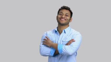 Kollarını kavuşturan esmer, neşeli bir adamın portresi..