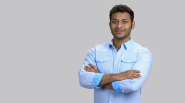 Kollarını kavuşturup arkasını gösteren mutlu esmer tenli adam..