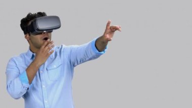 Şaşkın ve şoke olmuş koyu tenli genç adam VR-Kulaklık takıyor..